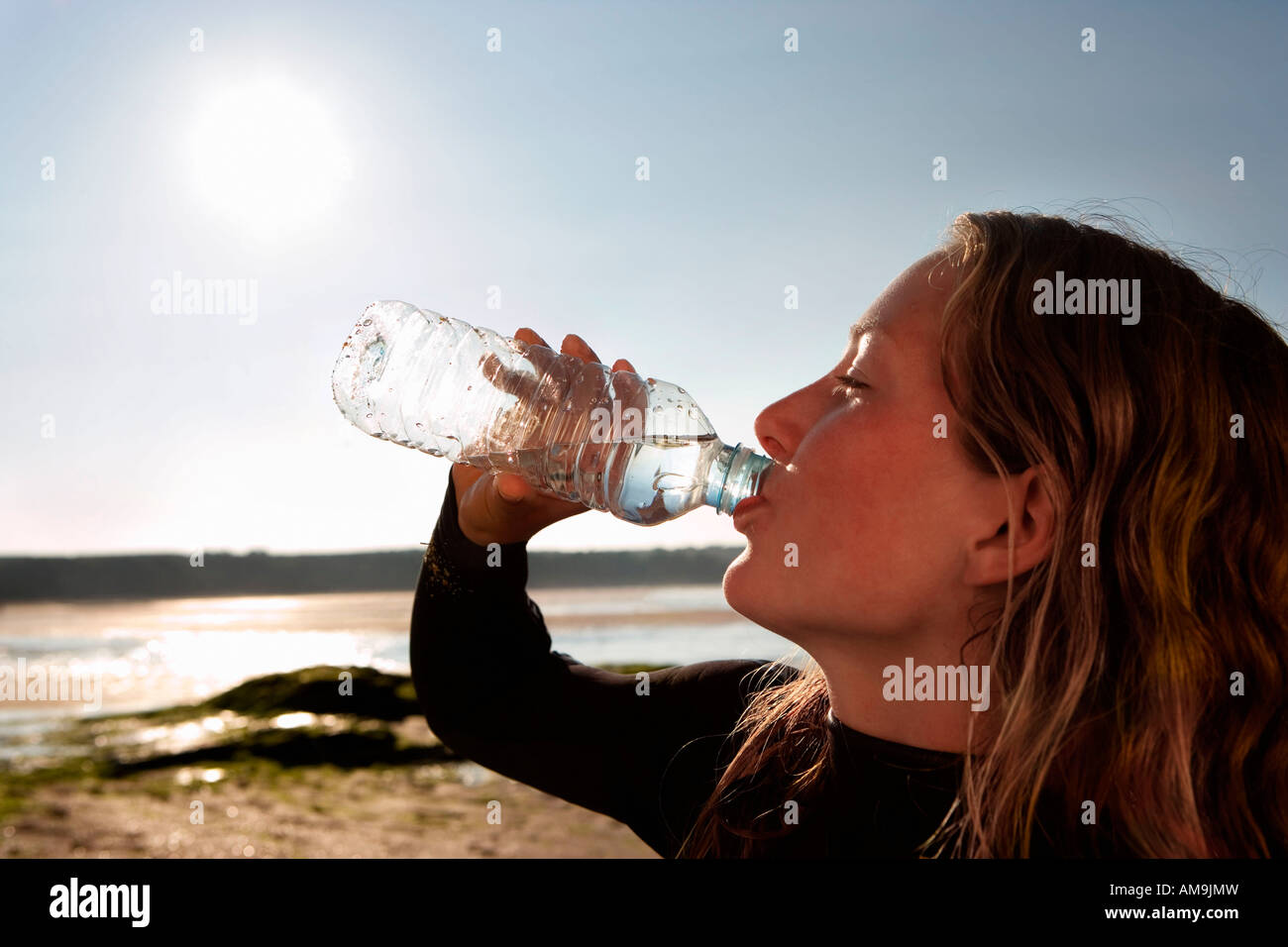 Woman drinking water in wetsuit. Stock Photo