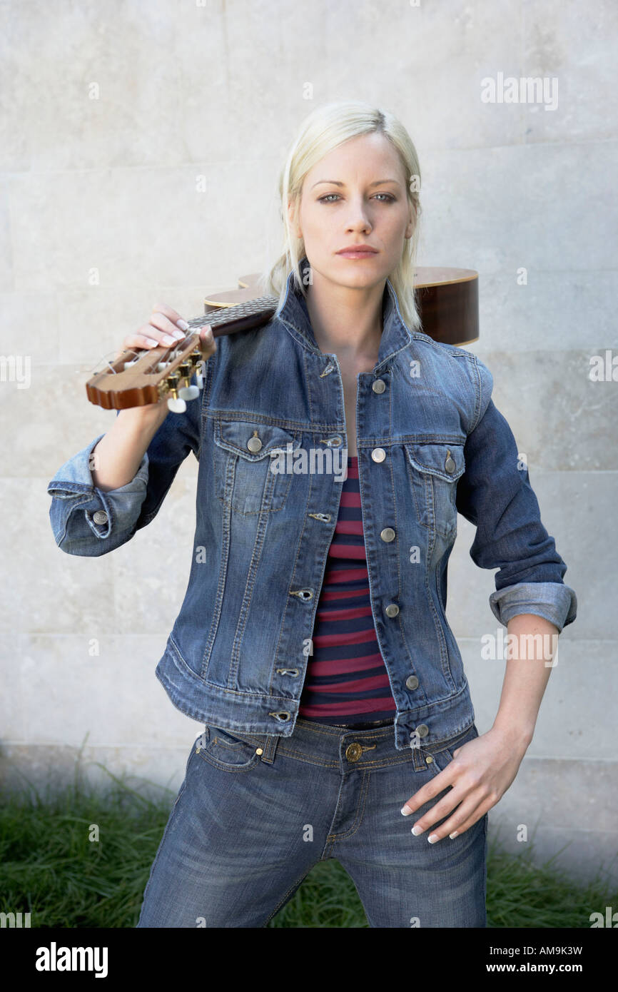 Woman standing holding a guitar Stock Photo - Alamy