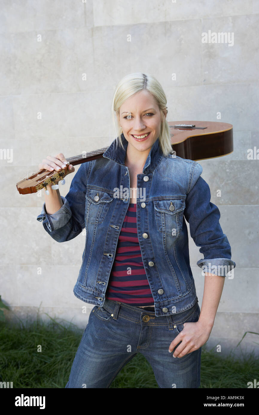 Woman standing holding a guitar smiling Stock Photo - Alamy