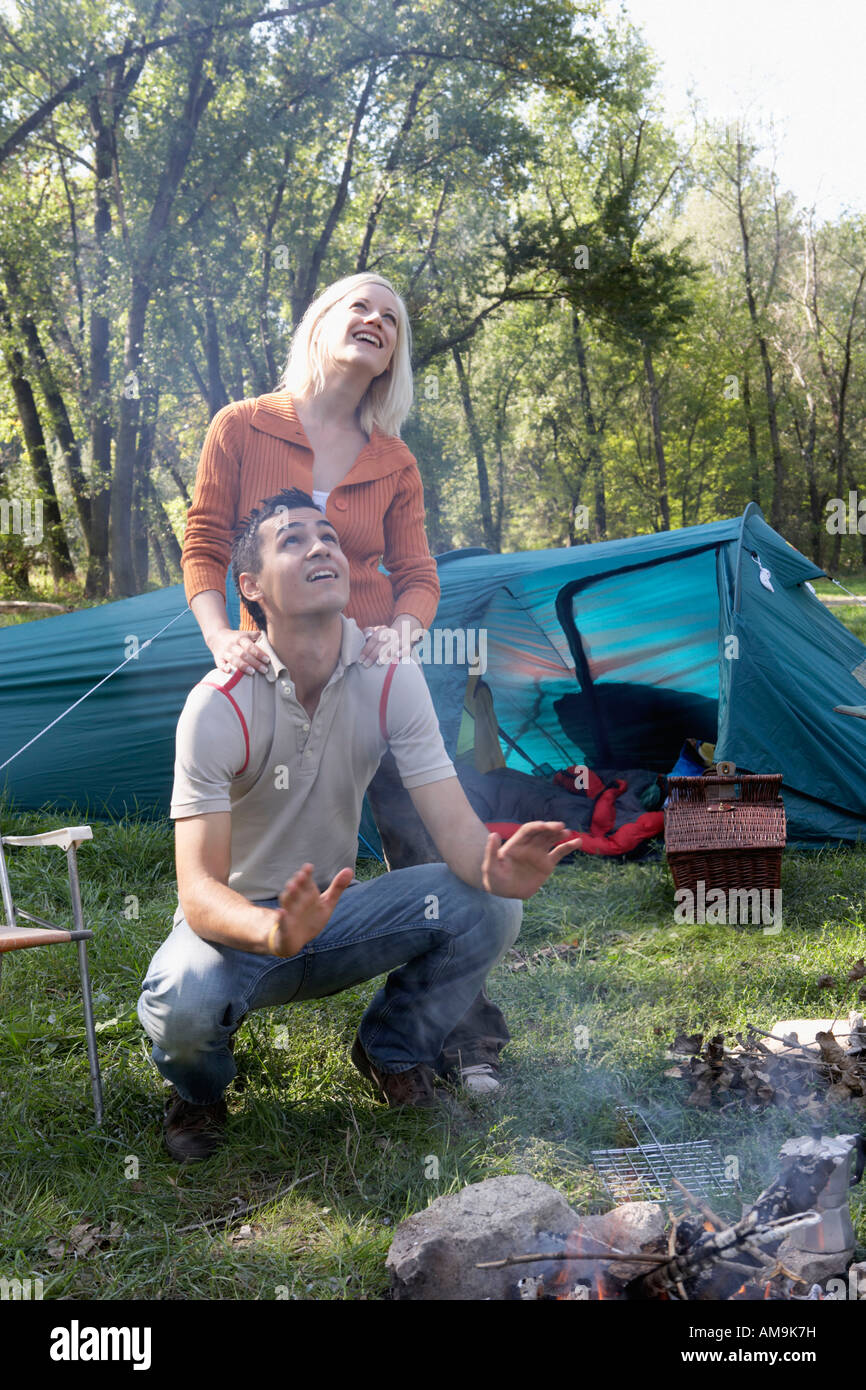 Couple At Campsite Looking Up At Smoke From The Fire Pit Smiling