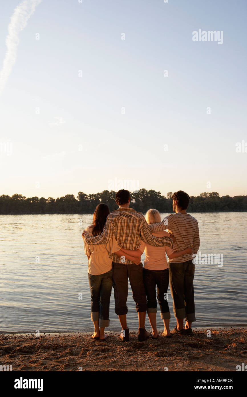 Four friends standing by a lake with arms around each other Stock Photo ...