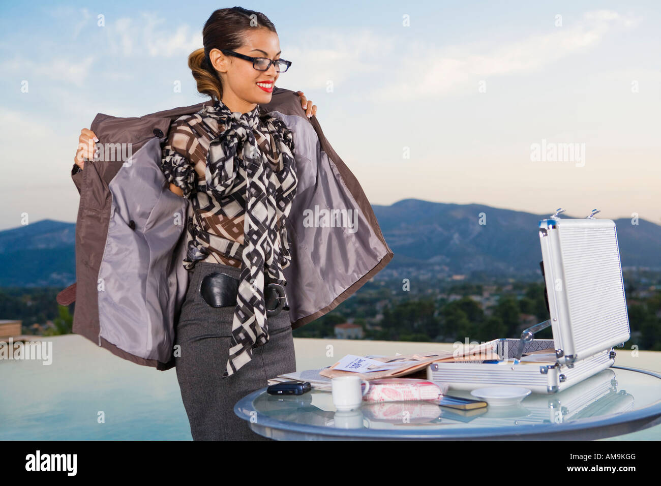 Woman putting on jacket while working at home outdoors Stock Photo Alamy