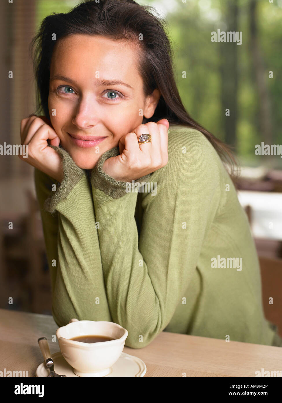 Woman with a mug at a table indoors smiling. Stock Photo