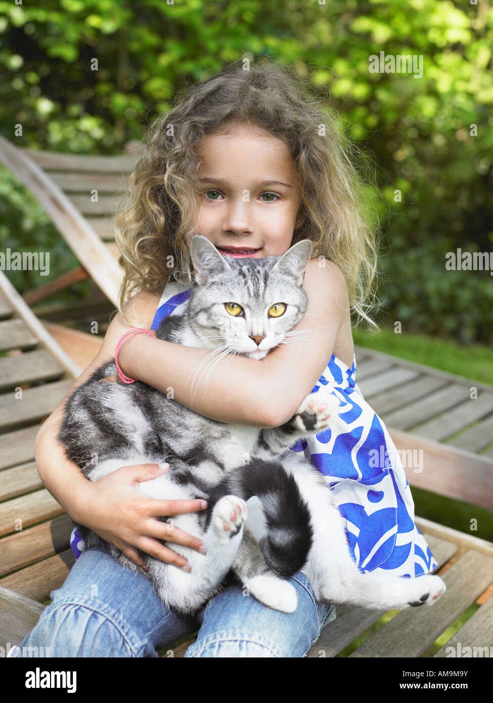 Young girl outdoors smiling with a cat on her lap. Stock Photo