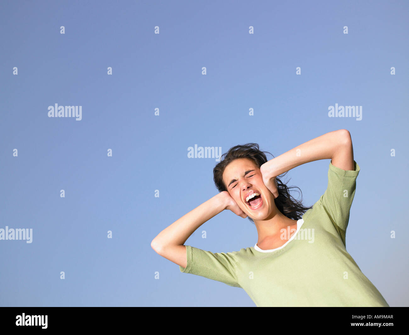 Woman covering ears and screaming outdoors. Stock Photo