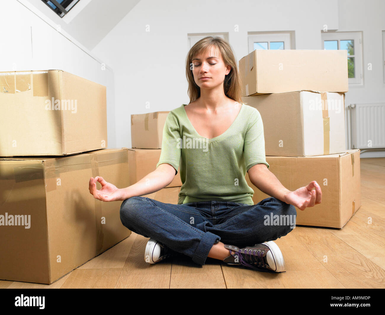 Woman doing yoga with moving boxes around her. Stock Photo