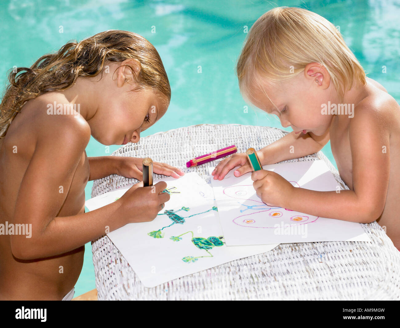 Two young children coloring by a pool. Stock Photo