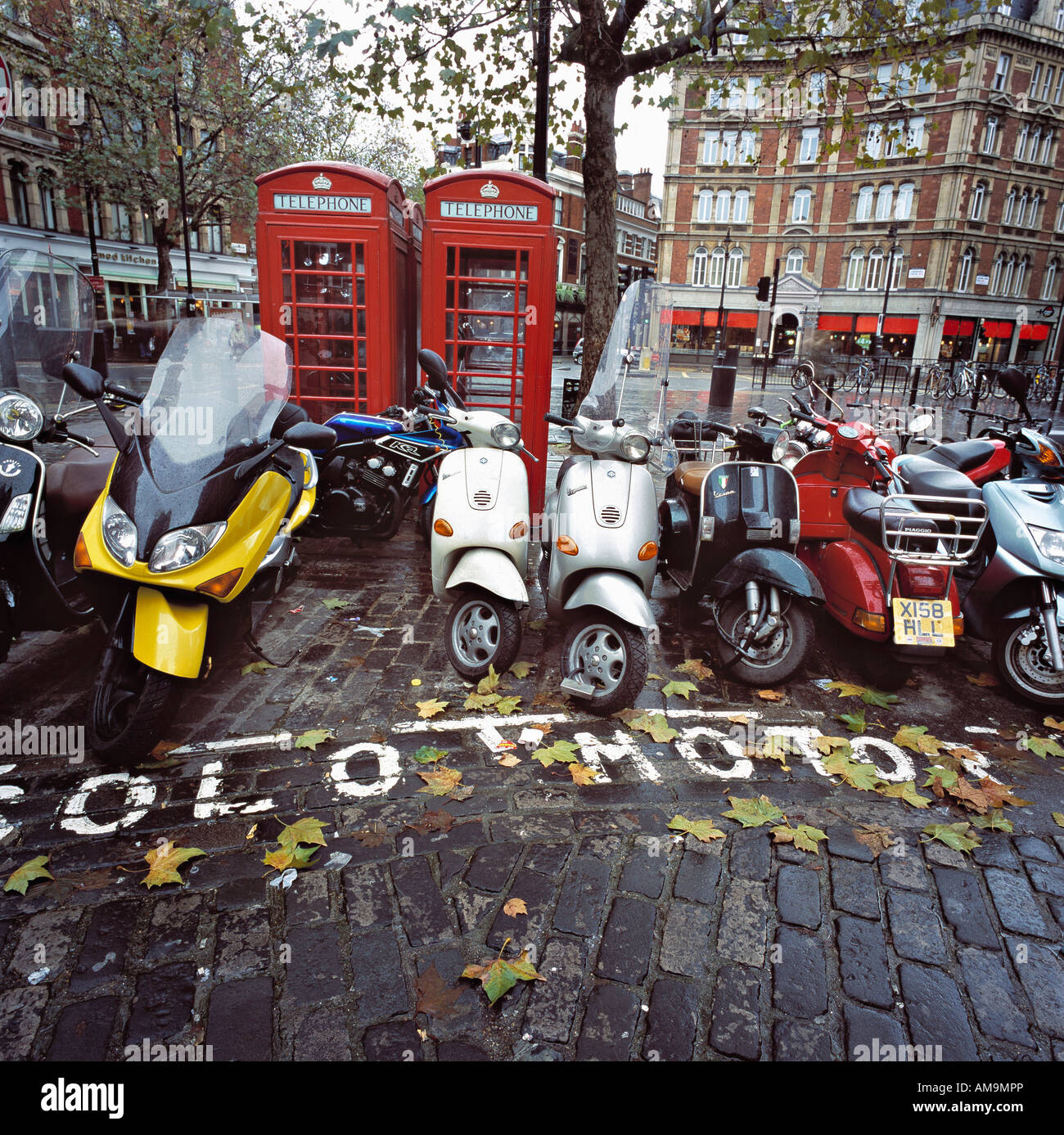 Parked motorbikes and scooters by phone booths in London. Stock Photo