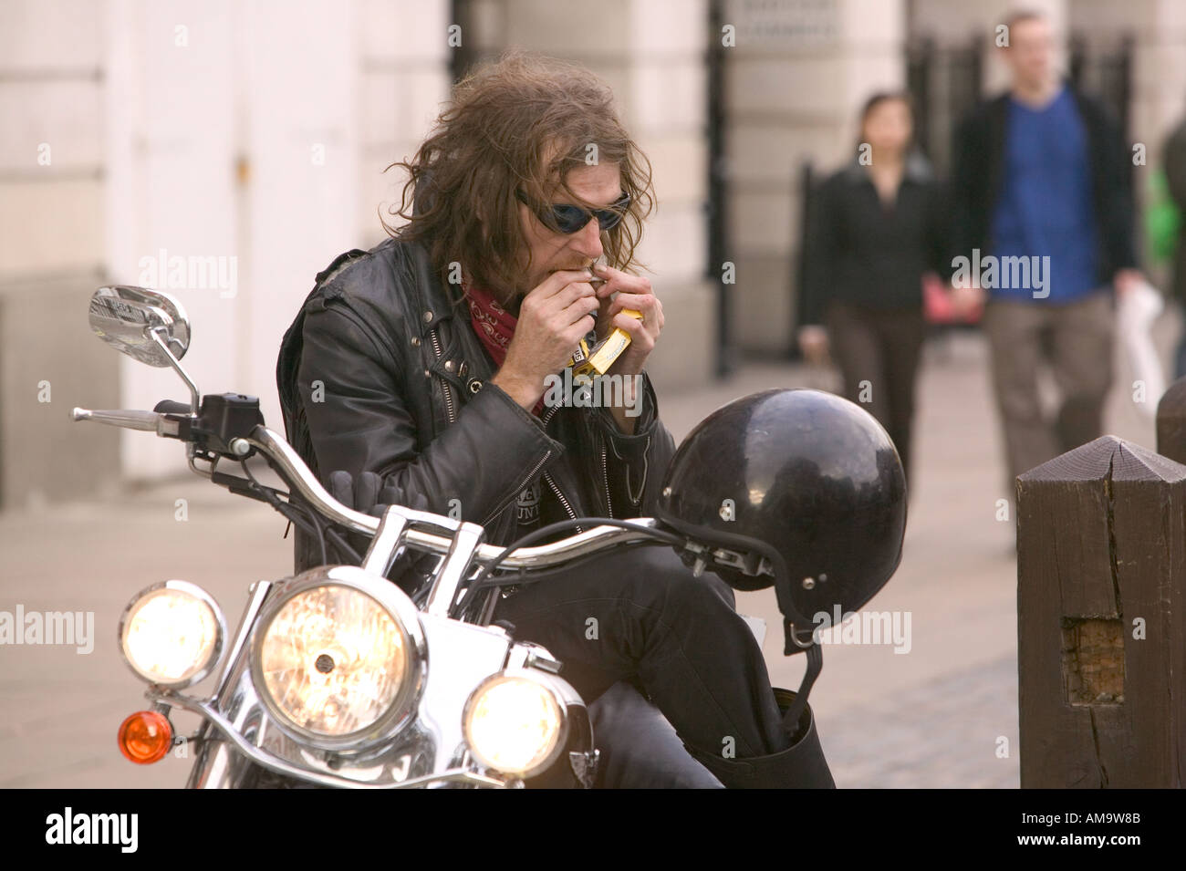 a biker rolling a hand rolled cigarette Covent garden London Stock Photo