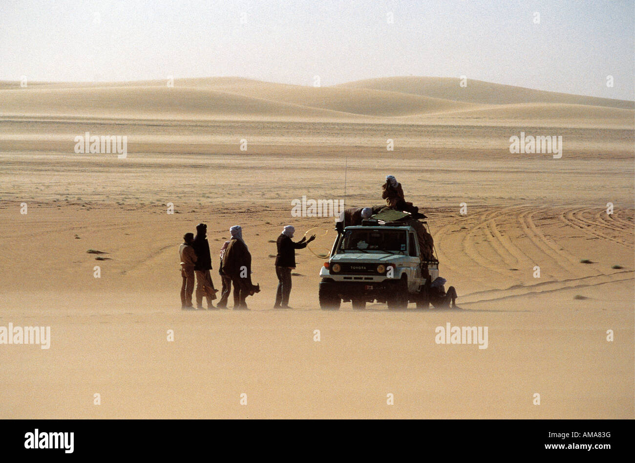 A Toyota pick up with seven 7 men pauses to refuel in the Great Sand Sea of Erg du D jourab Chad Africa Stock Photo
