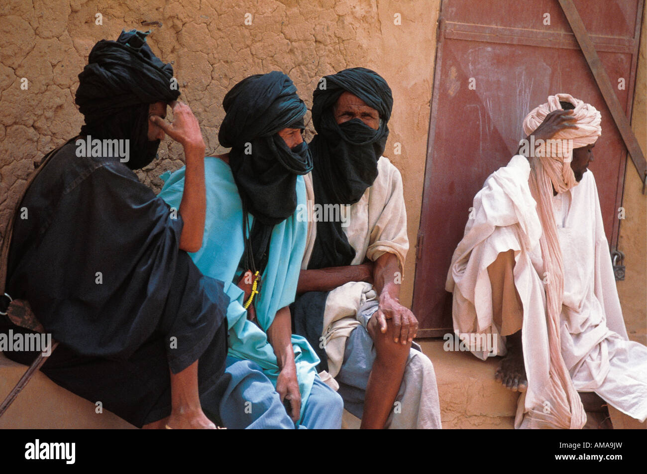 Four 4 Tuareg men wearing long robes and turbans sitting and chatting in Mali Africa Stock Photo