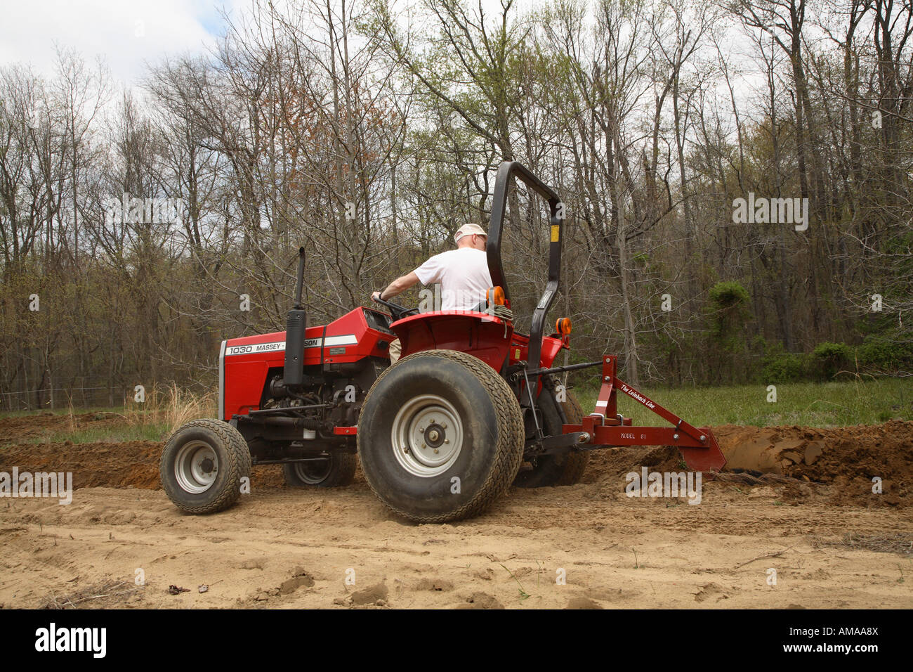 Man driving a small tractor ploughing or plowing field on specialist