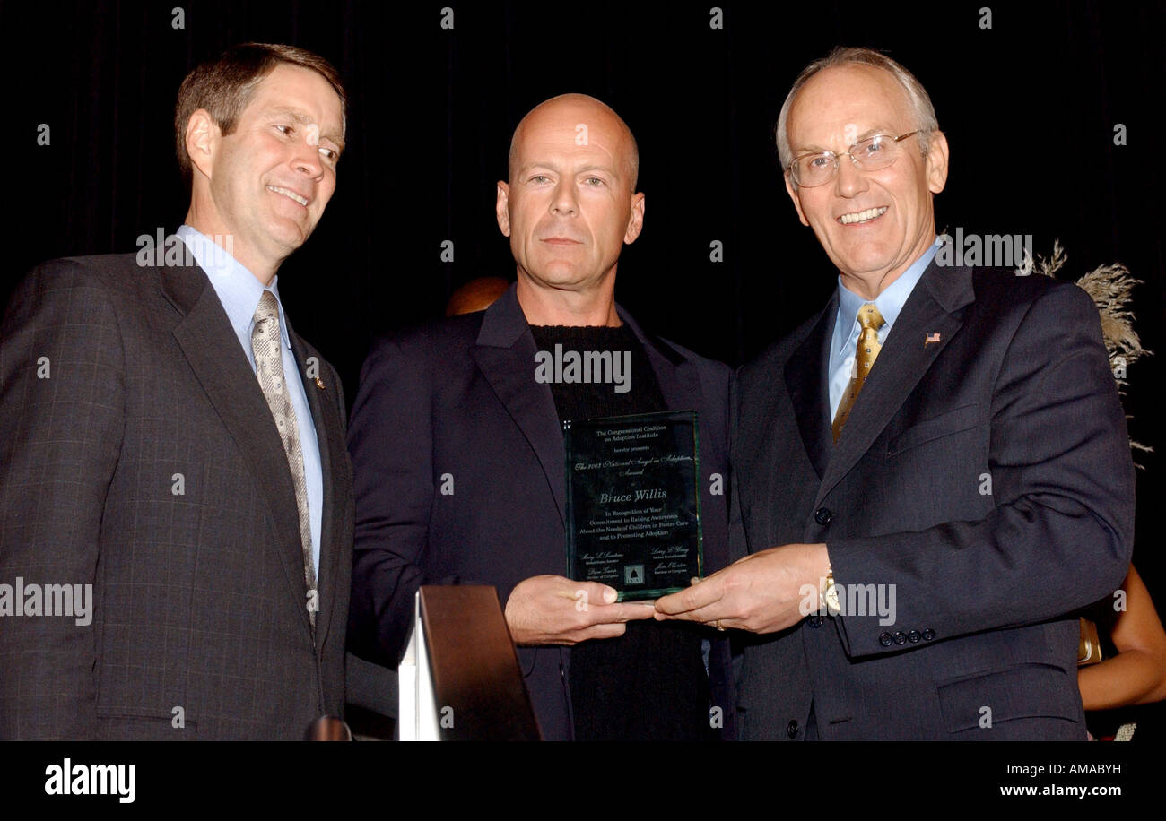 Sen Bill Frist R TN Bruce Willis and Sen Larry Craig R ID stands on stage at the Congressional Coalition on Adoption Institue s Stock Photo