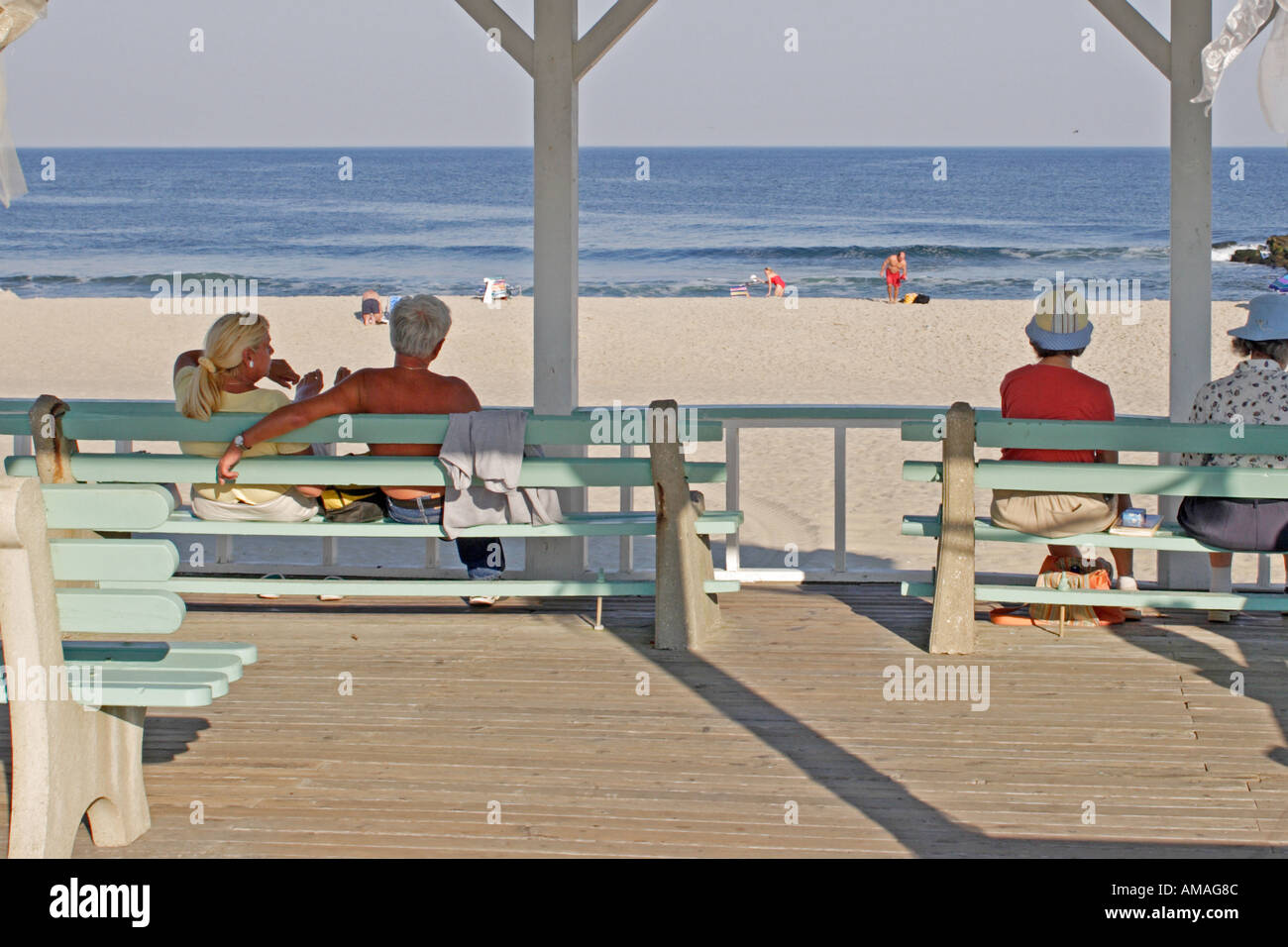 Some older people on the boardwalk look out at the ocean Stock Photo