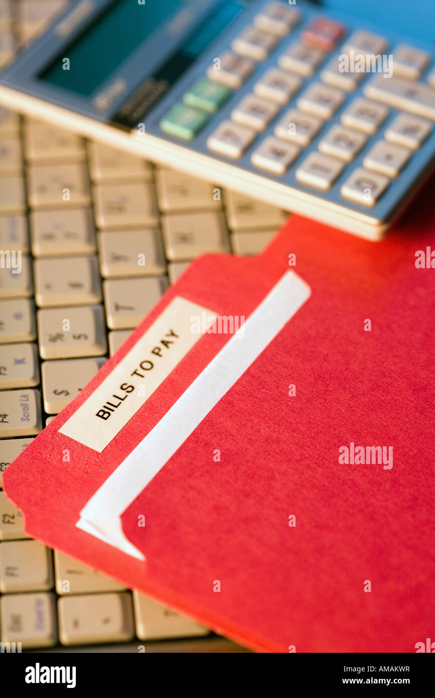 File with bills by a calculator and laptop Stock Photo - Alamy