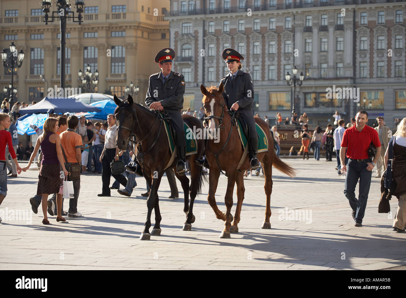 TWO MOUNTED POLICE OFFICERS RIDING HORSES THROUGH CROWDS IM MANEZHNAYA SQUARE MOSCOW RUSSIA Stock Photo