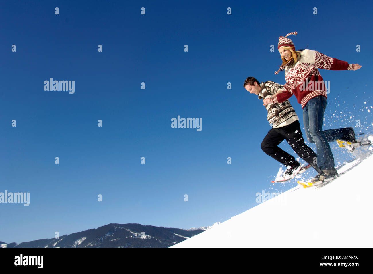 Young couple in snow, running downhill Stock Photo