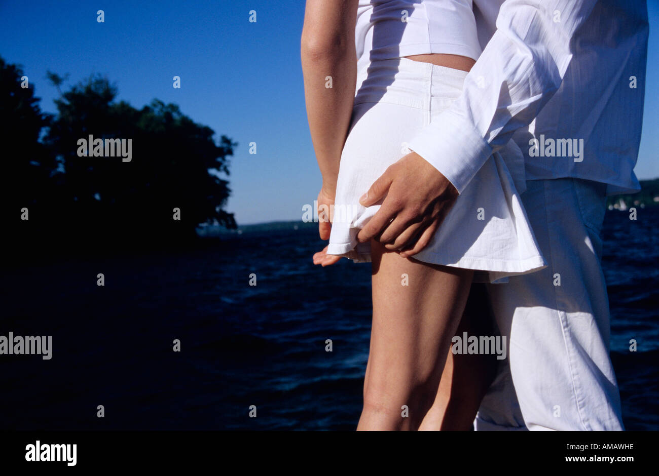 Young couple standing by lake, mid section, side view Stock Photo
