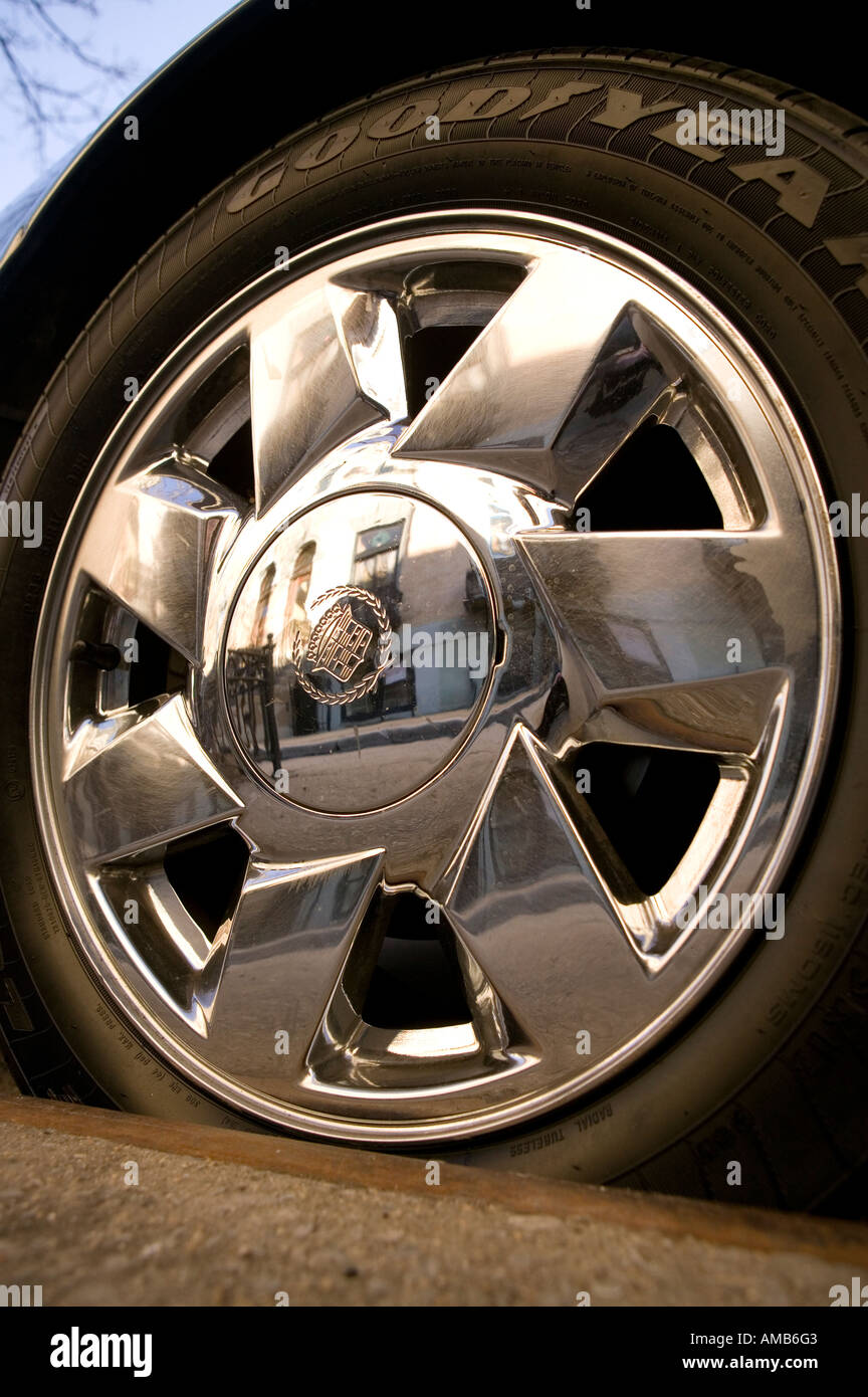 Metal wheel hubcap and Goodyear tire on a car parked by the sidewalk