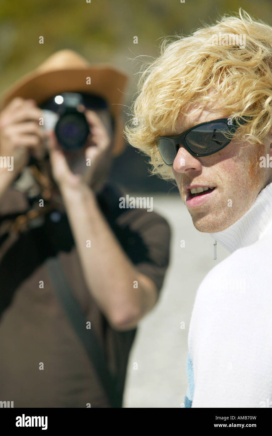 man with blond hair and sunglasses is posing for photographs Stock Photo