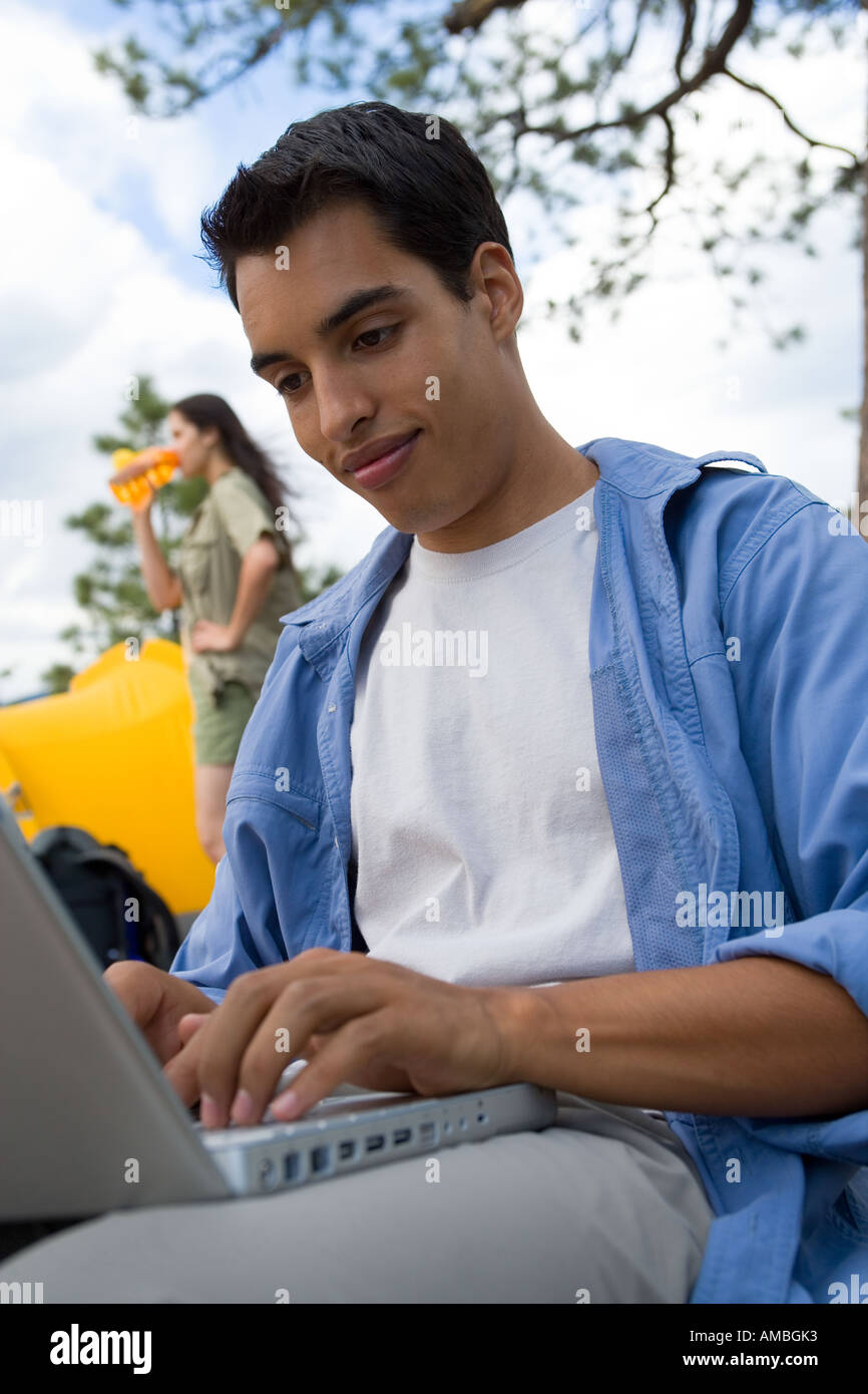 young man at campsite using laptop computer Stock Photo