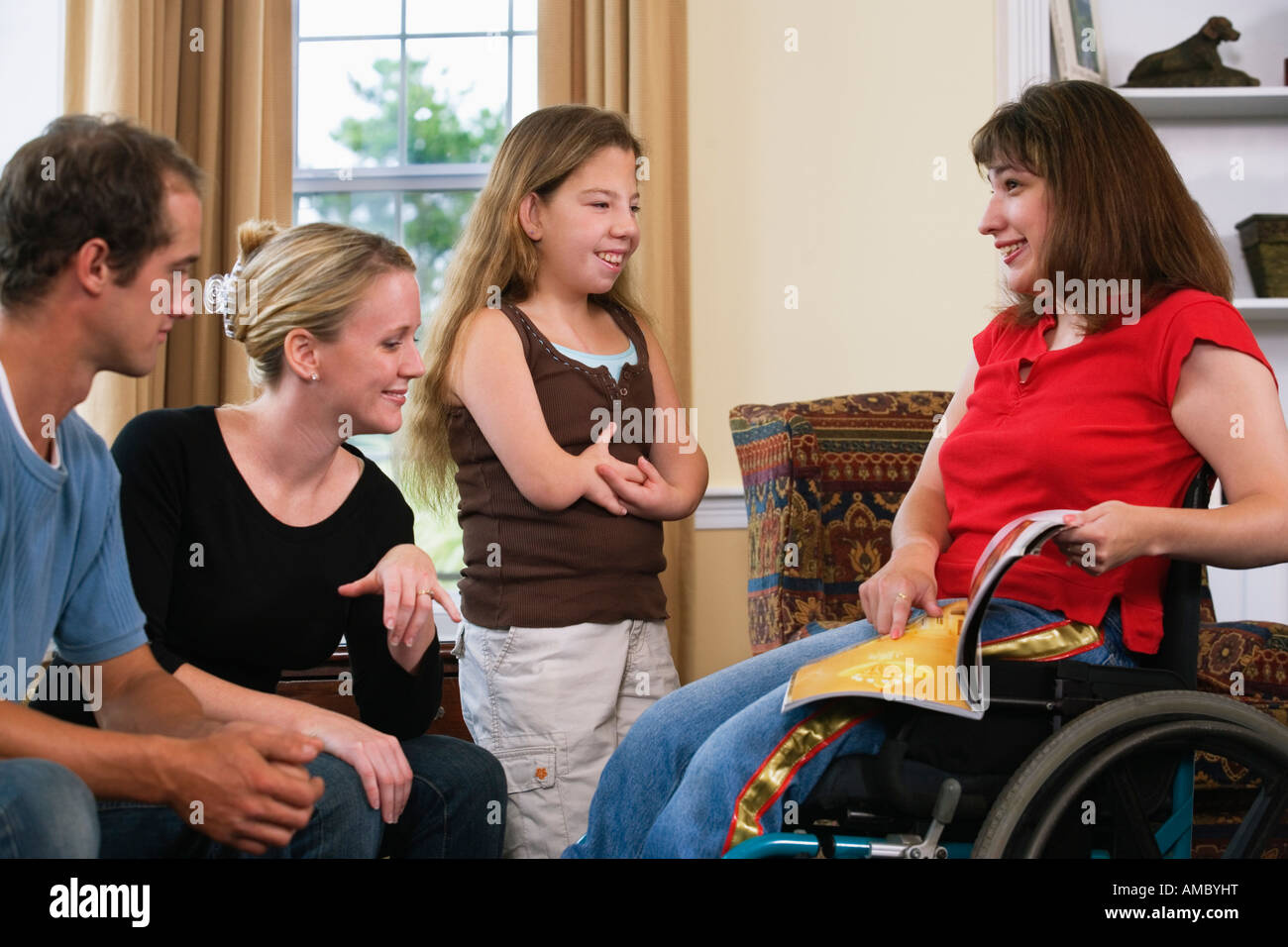 A happy family sitting together with hand deformity, wheelchair and signing. Stock Photo