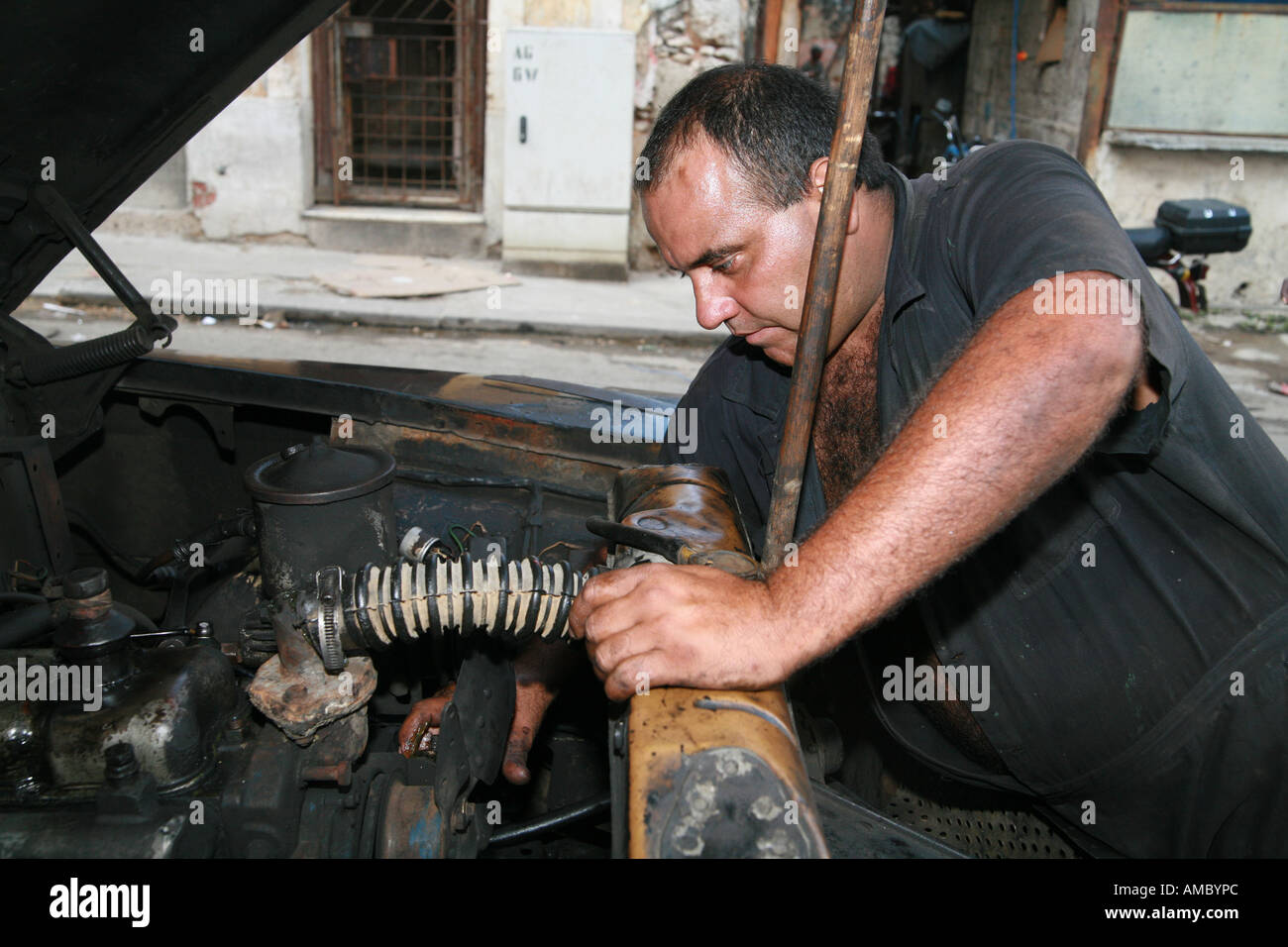 Havana Cuba a private taxi driver working on his 59year old classic car all original except the engine Stock Photo