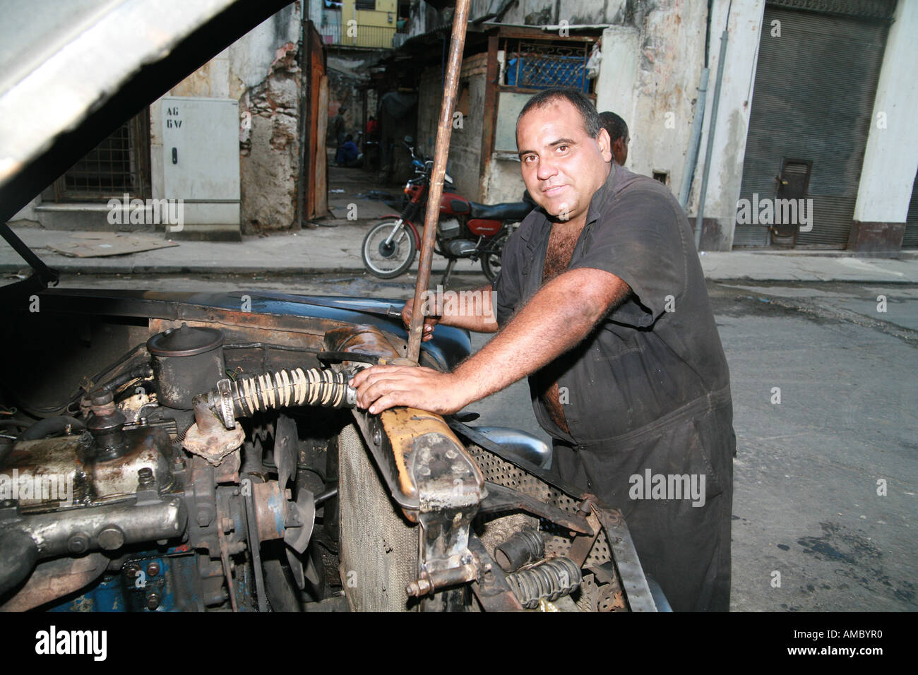 Havana Cuba a private taxi driver working on his 59year old classic car all original except the engine Stock Photo