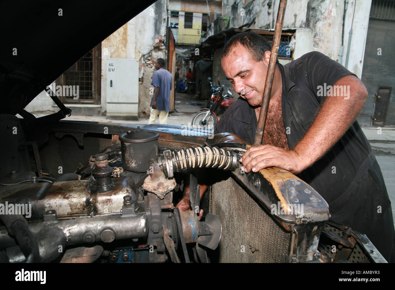 Havana Cuba a private taxi driver working on his 59year old classic car all original except the engine Stock Photo