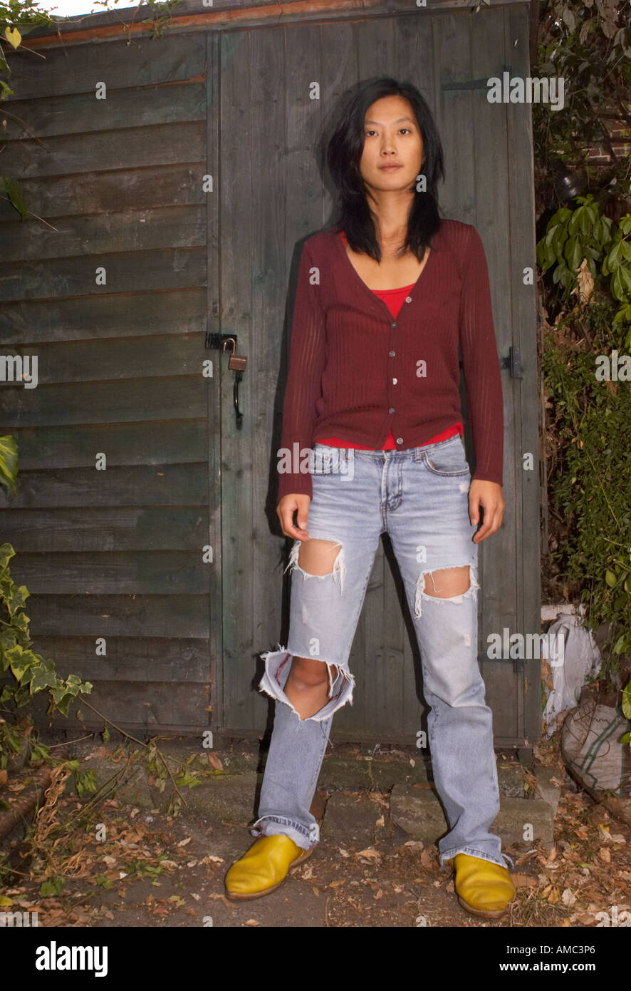 role reversal of young confident oriental woman in casual clothes guarding her shed Stock Photo