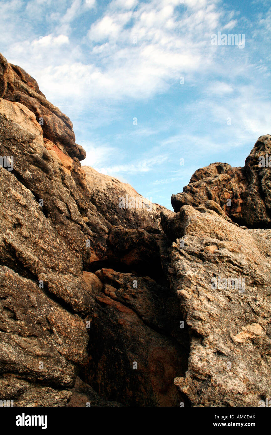 Rocky jagged cliff with sky and wispy clouds in the background Stock Photo