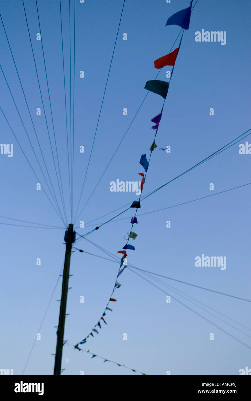 looking up at bunting with coloured flags hanging from telephone pole ...