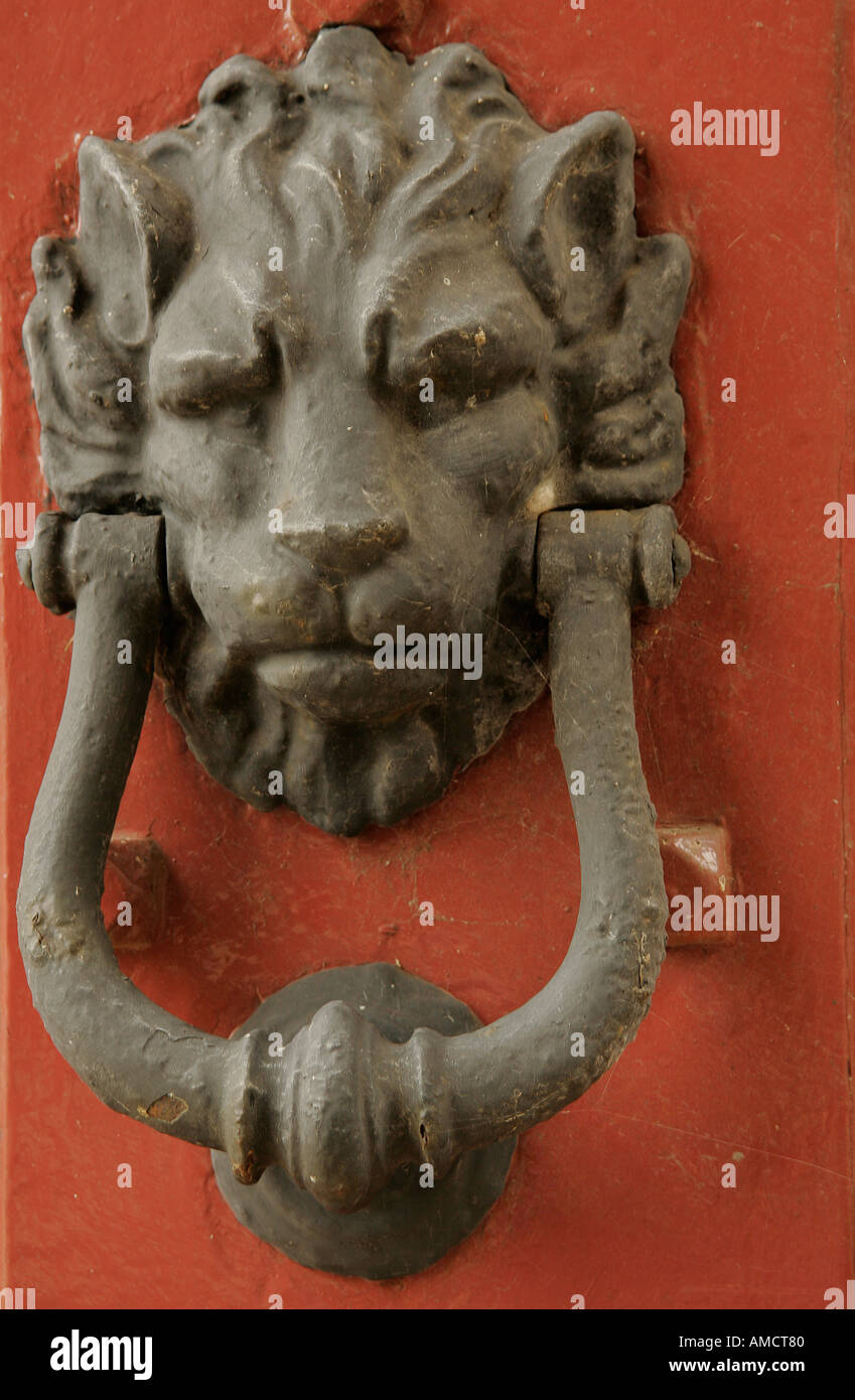 Door knocker in shape of a lions head against a red painted door Stock Photo