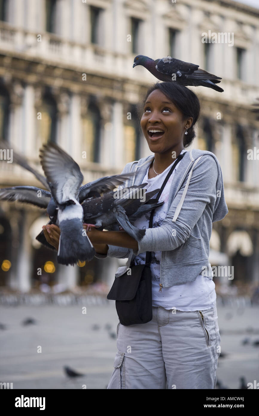 Woman in square with pigeon on head smiling Stock Photo