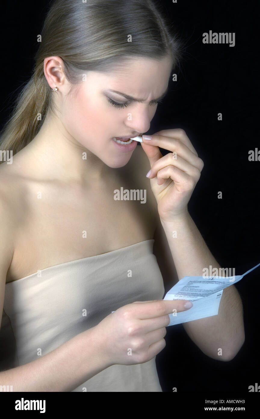 Woman taking pill and reading enclosing note Stock Photo