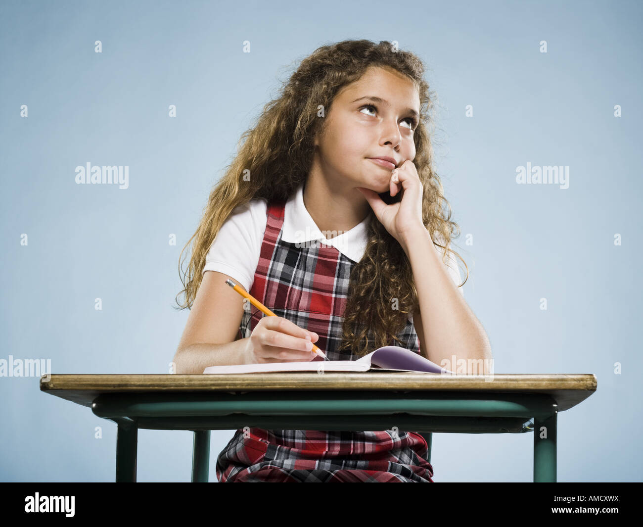 Girl sitting at desk with workbook looking bored Stock Photo - Alamy