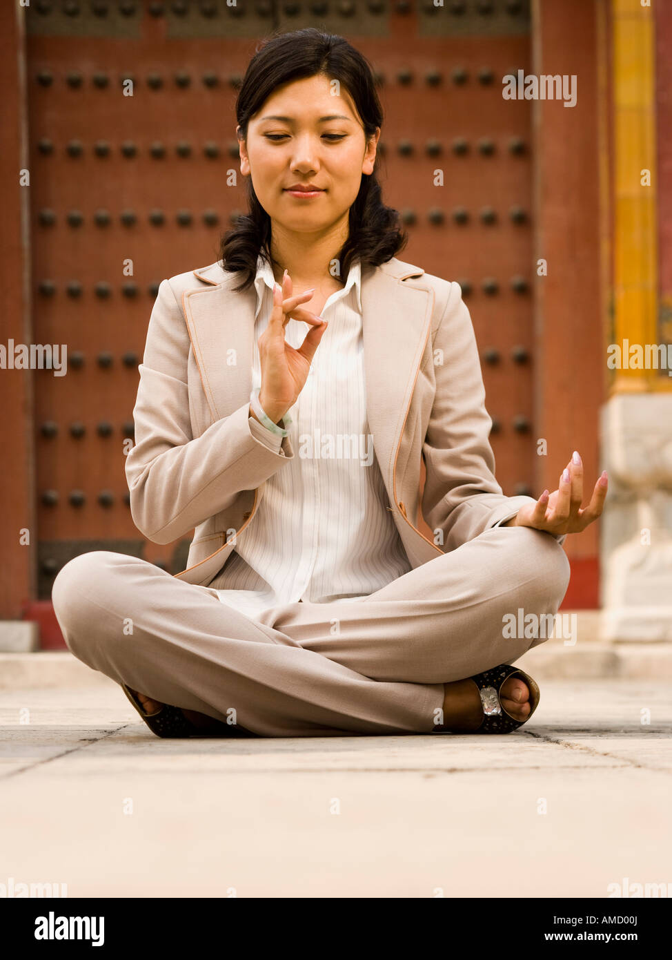 Businesswoman sitting cross legged outdoors meditating Stock Photo - Alamy