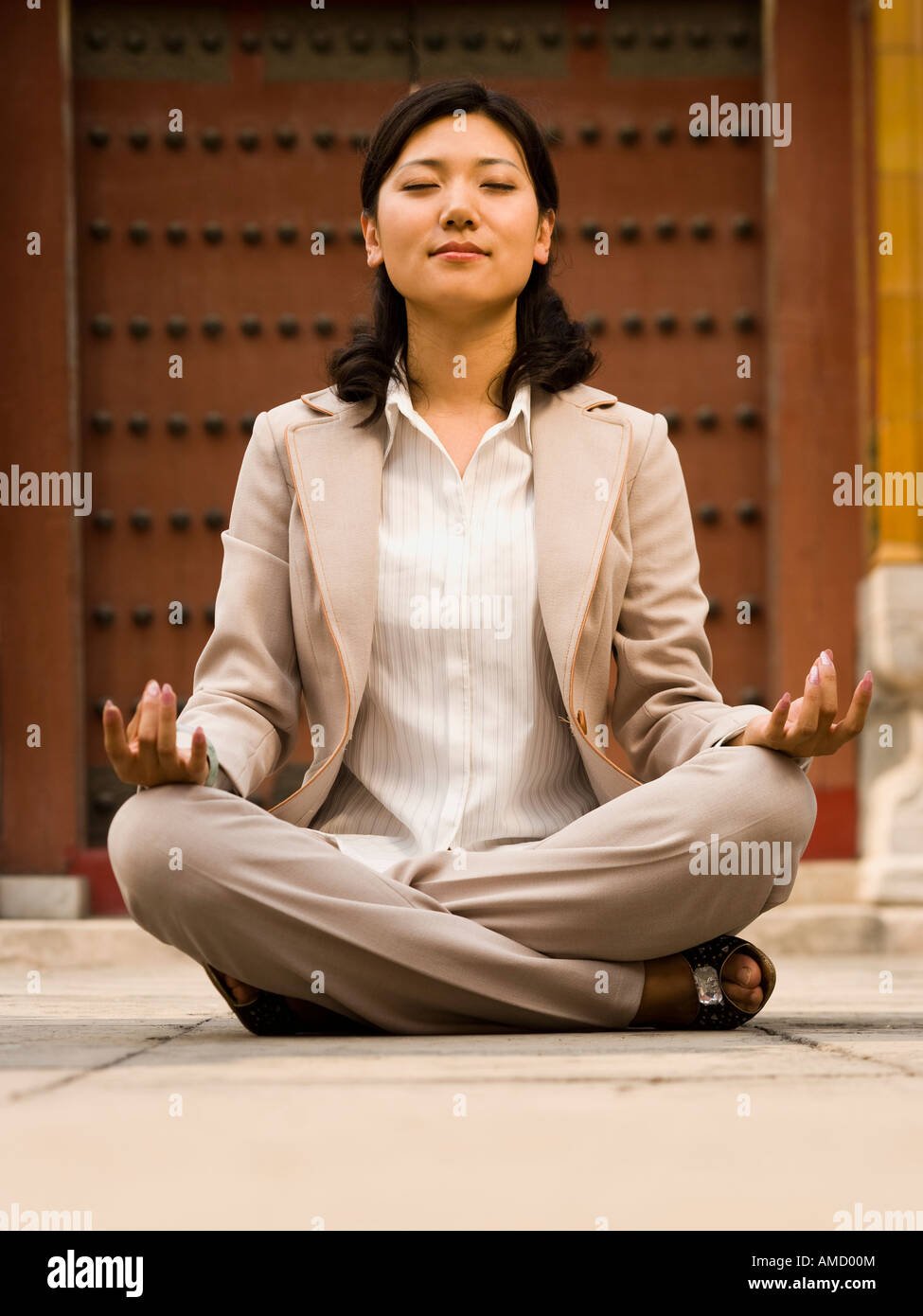 Businesswoman sitting cross legged outdoors meditating Stock Photo - Alamy