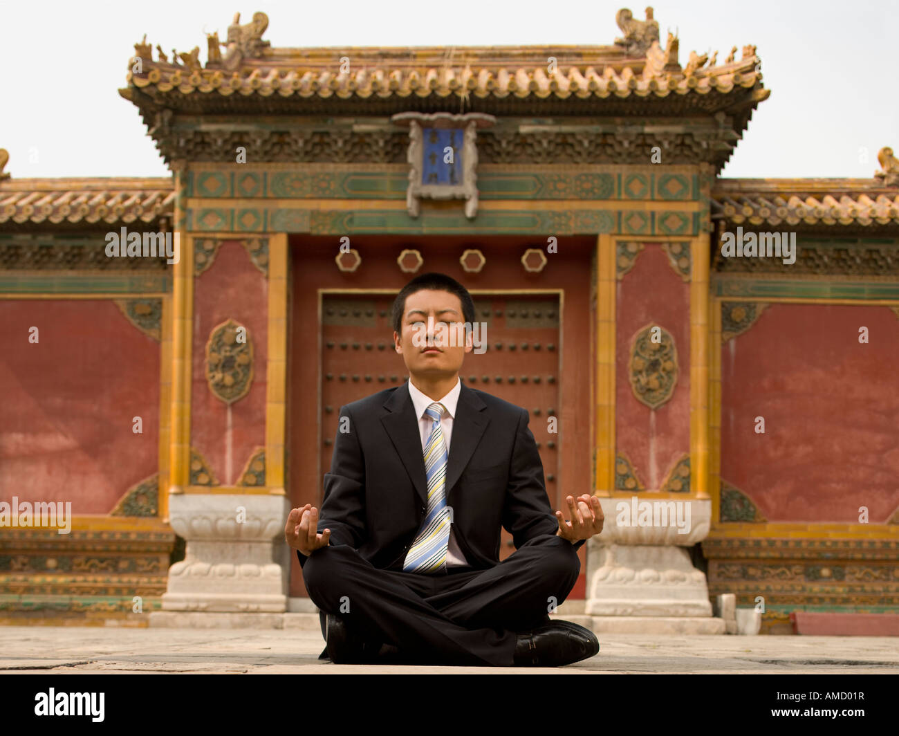 Businessman sitting cross legged outdoors meditating Stock Photo - Alamy