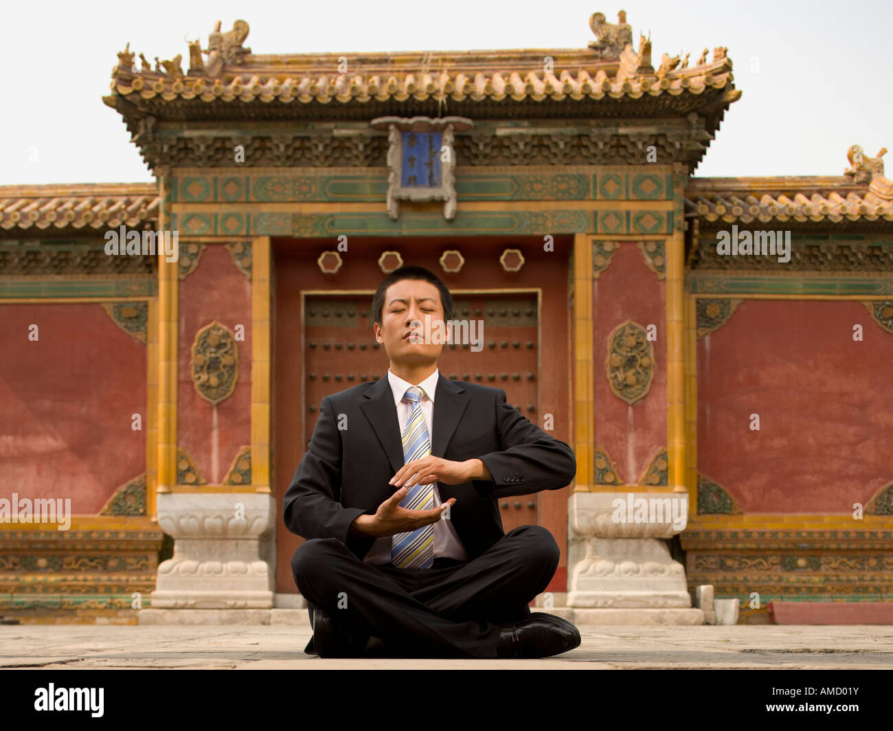Businessman sitting cross legged outdoors meditating Stock Photo - Alamy