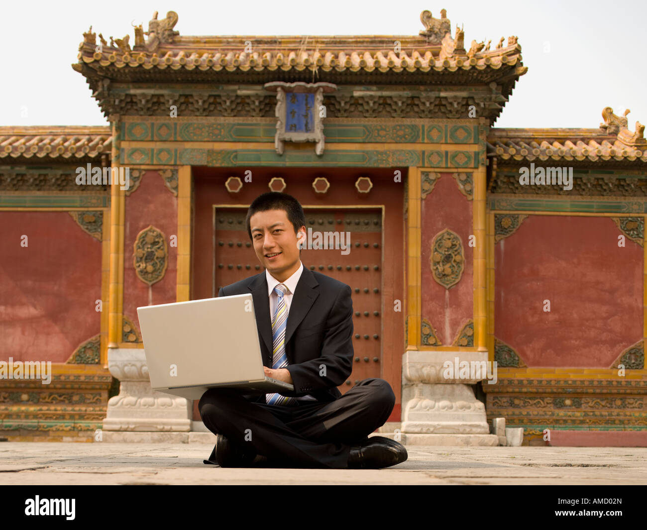 Businessman sitting cross legged outdoors with laptop Stock Photo - Alamy