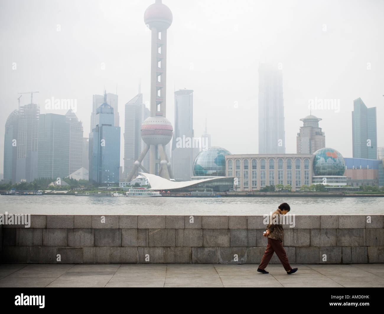Man walking along waterfront with city skyline Stock Photo