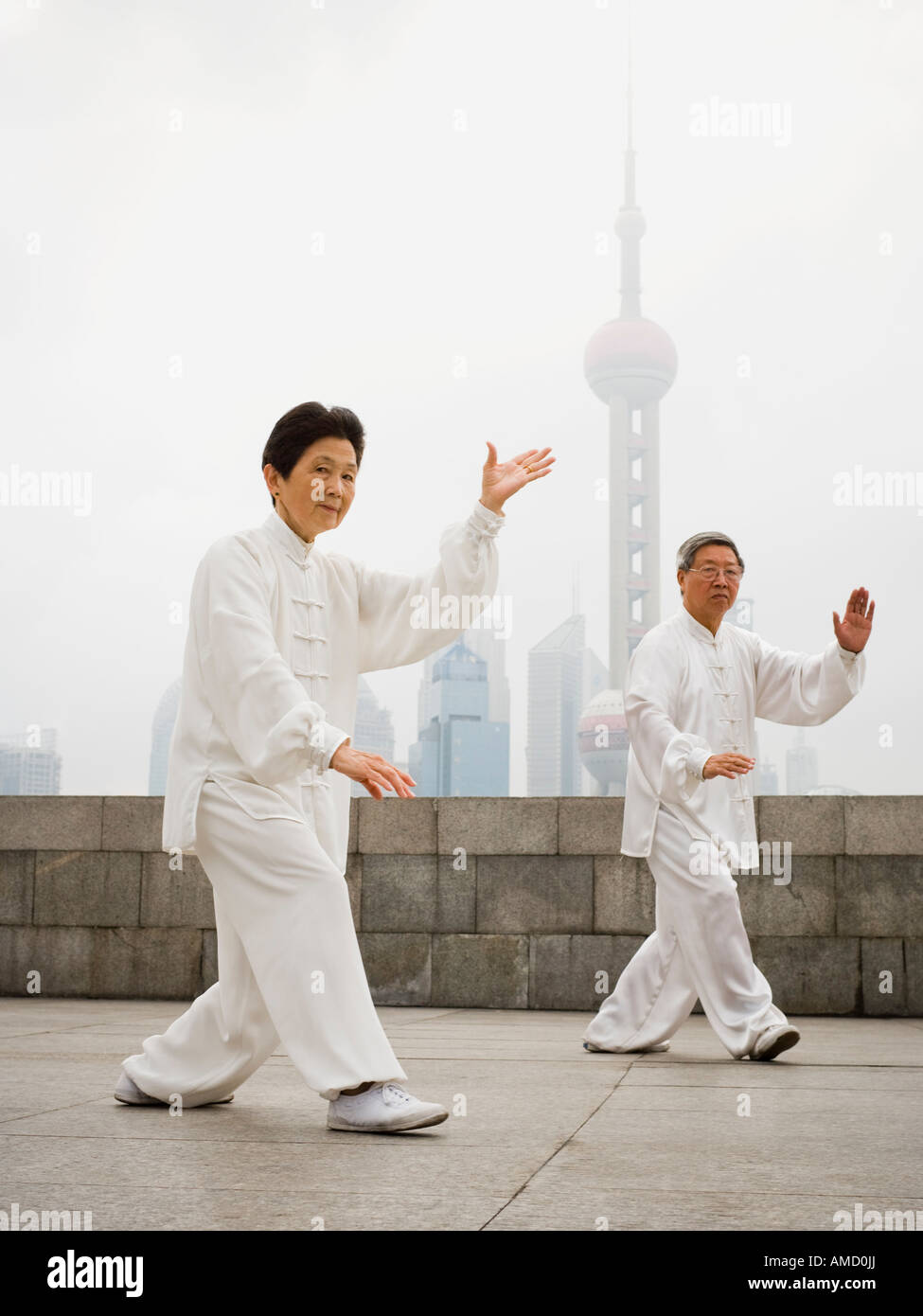 Couple doing tai chi outdoors with city skyline in background Stock Photo