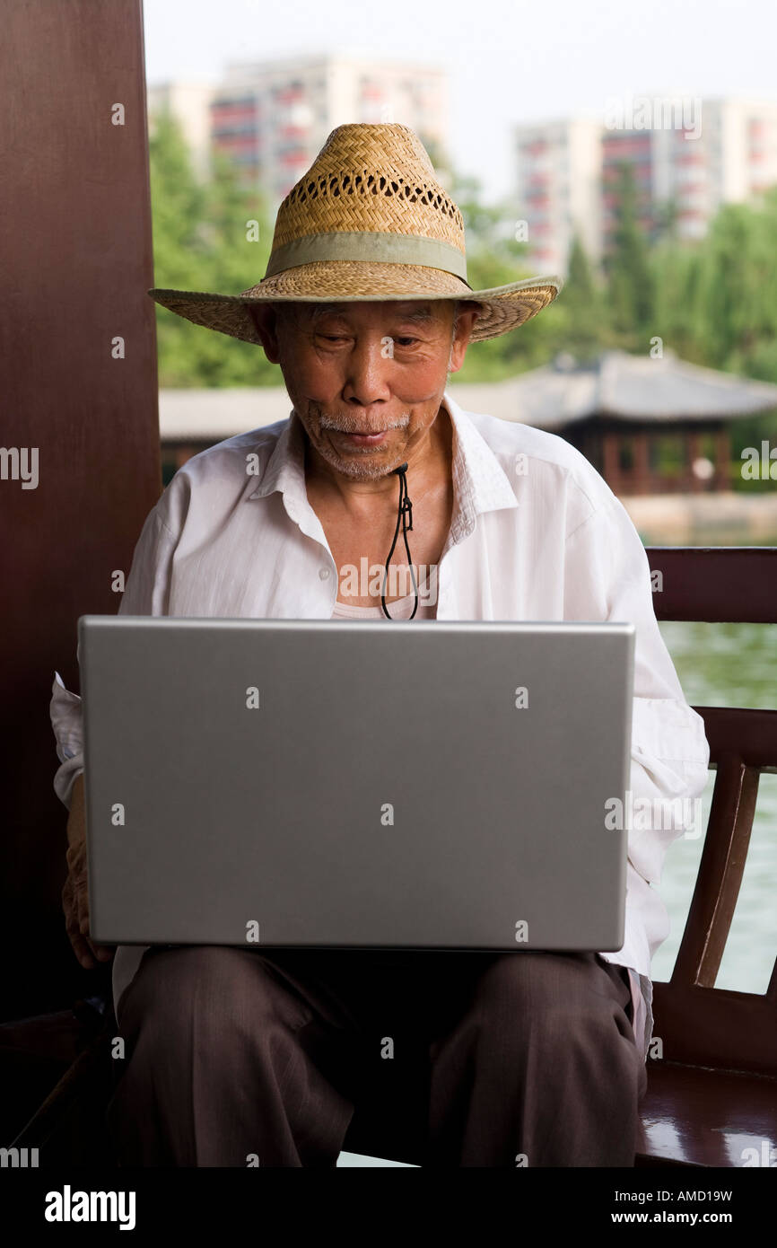 Mature man with straw hat and laptop outdoors Stock Photo