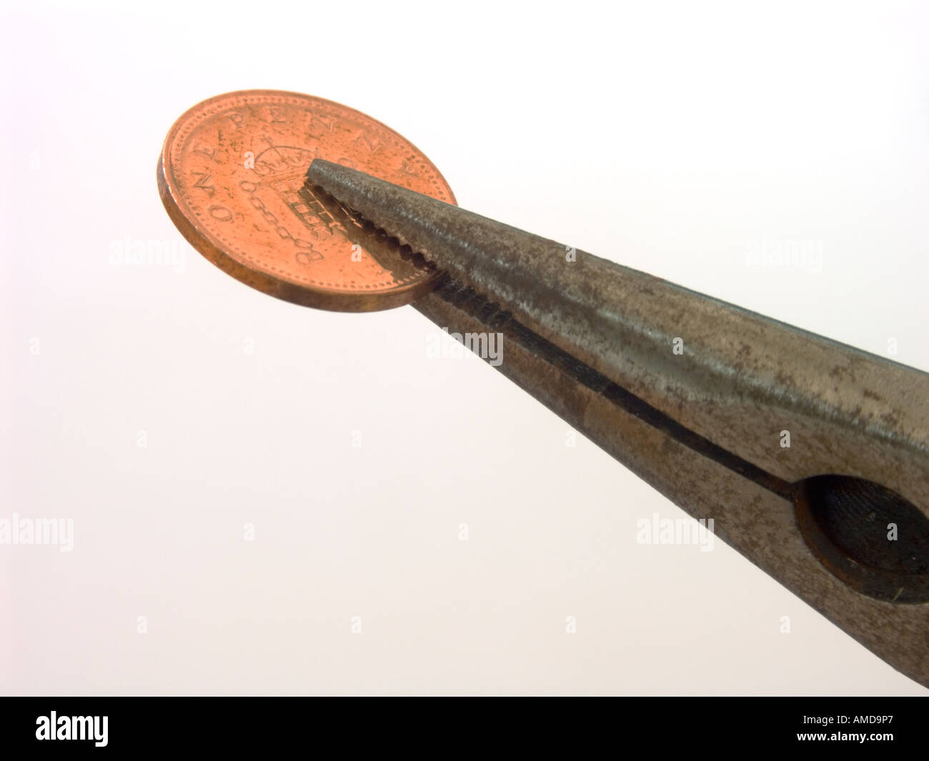 Penny pinching. A penny gripped by pliers Stock Photo Alamy