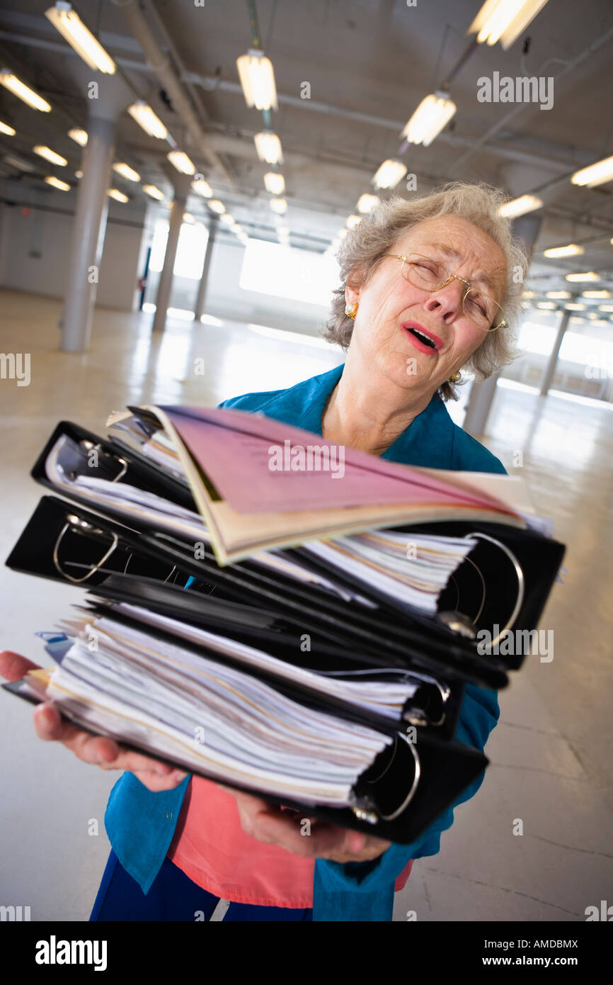 View of a senior woman carrying heavy files. Stock Photo