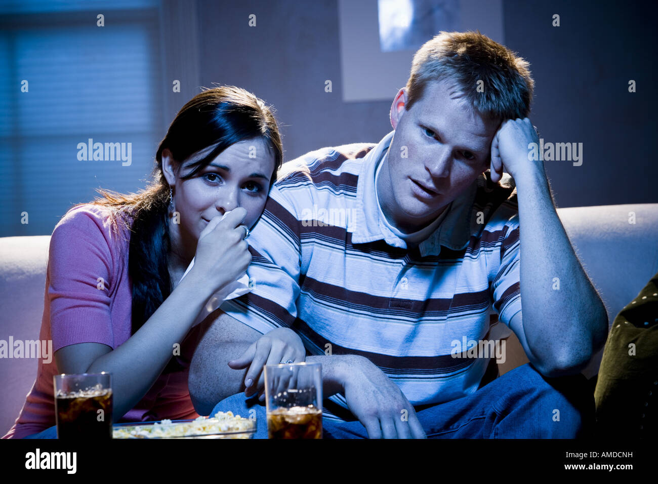 Couple watching television with bowl of popcorn looking sad Stock Photo