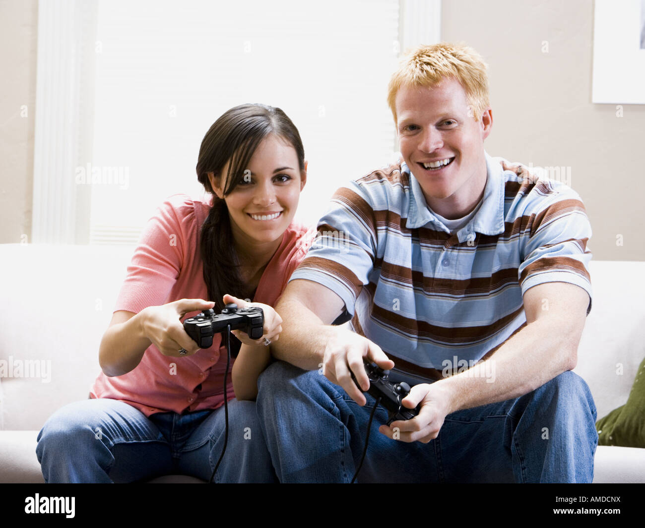 Man and woman on sofa playing video games Stock Photo