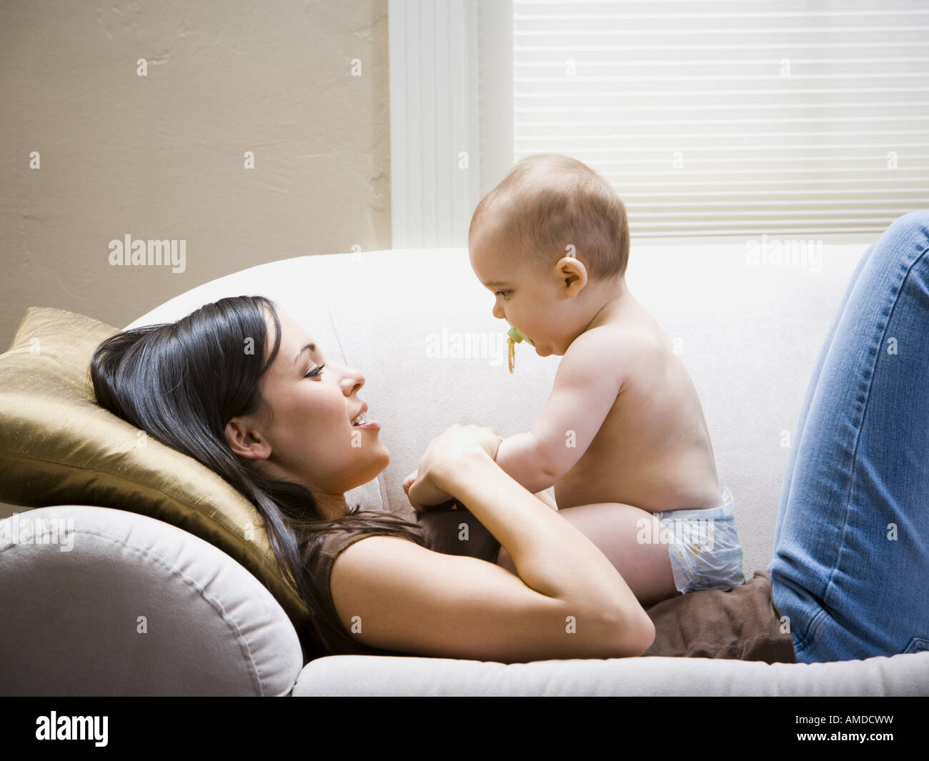 Woman lying down on sofa with baby Stock Photo