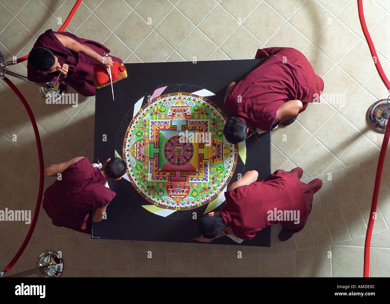 Four monks work on a nearly completed mandala Stock Photo